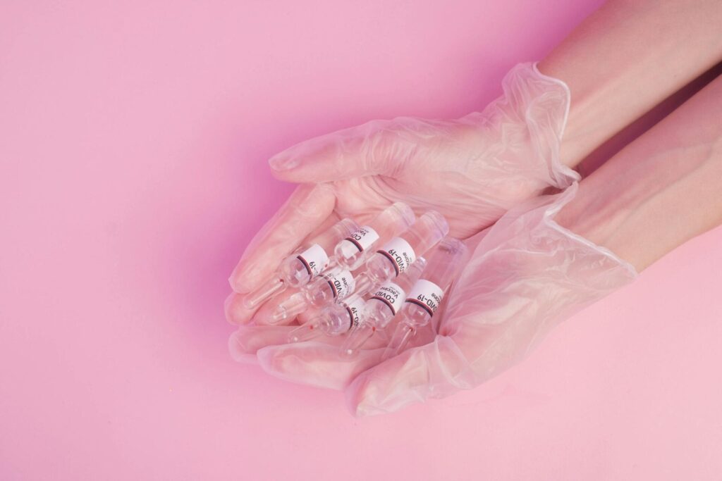 Gloved hands holding COVID-19 vaccine vials.