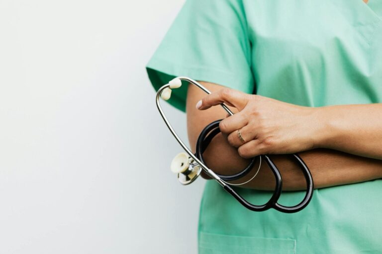 Nurse holding stethoscope in green scrubs