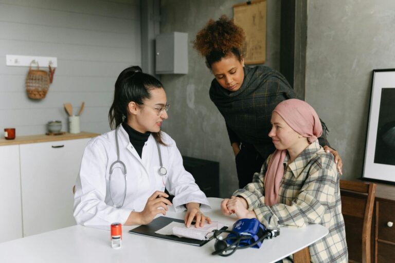 Doctor consults patient with supportive friend nearby.