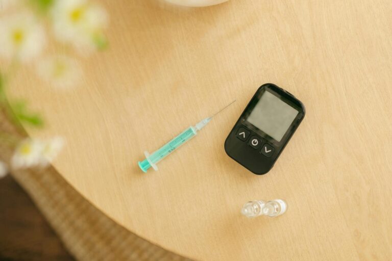 Diabetes kit: syringe, monitor, insulin bottles on table.